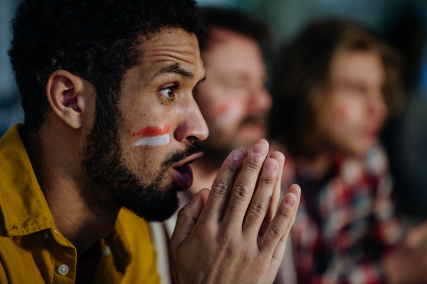 Nervous football fans friends watching a German national team in live soccer match on TV at home