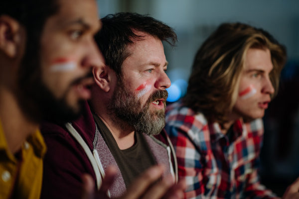 Nervous football fans friends watching a German national team in live soccer match on TV at home