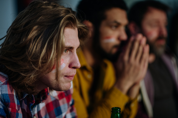 Nervous football fans friends watching match on a TV at home and praying.