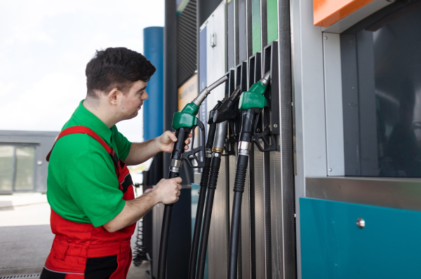 A Down syndrome man employee fueling car at gas station.