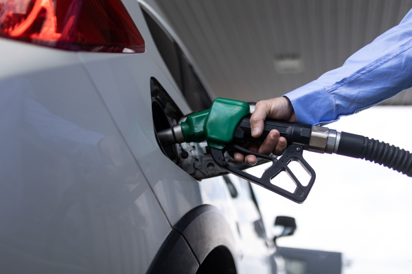 A hand refilling the car with fuel at the refuel station