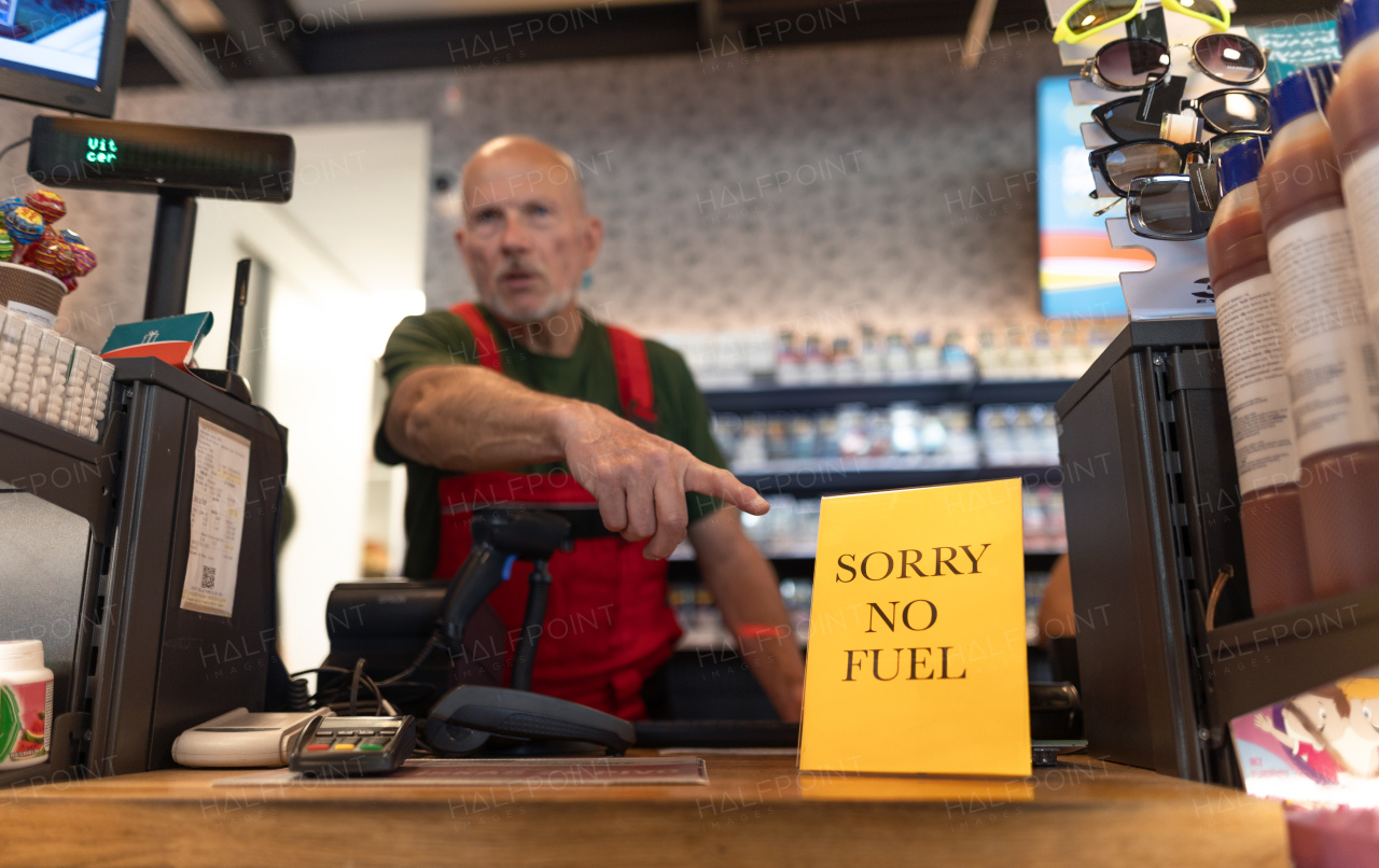 A senior worker pointing on no fuel sign on petrol station due to economic crisies