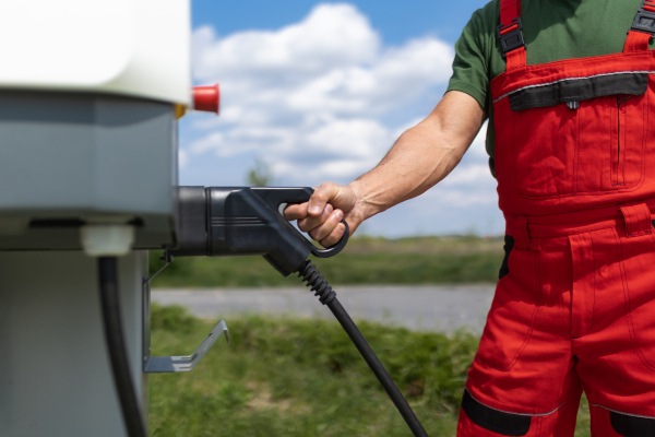 A senior worker standing on gas station and fueling car.