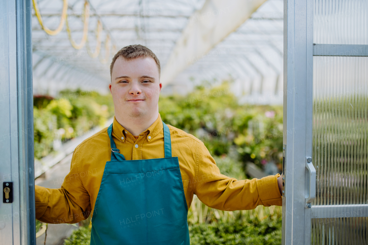 A young employee with Down syndrome working in garden centre, looking at camera.