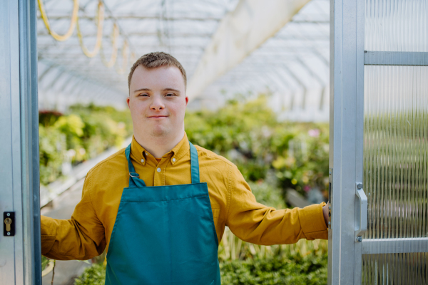 A young employee with Down syndrome working in garden centre, looking at camera.