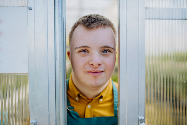 A young employee with Down syndrome working in garden centre, looking at camera.