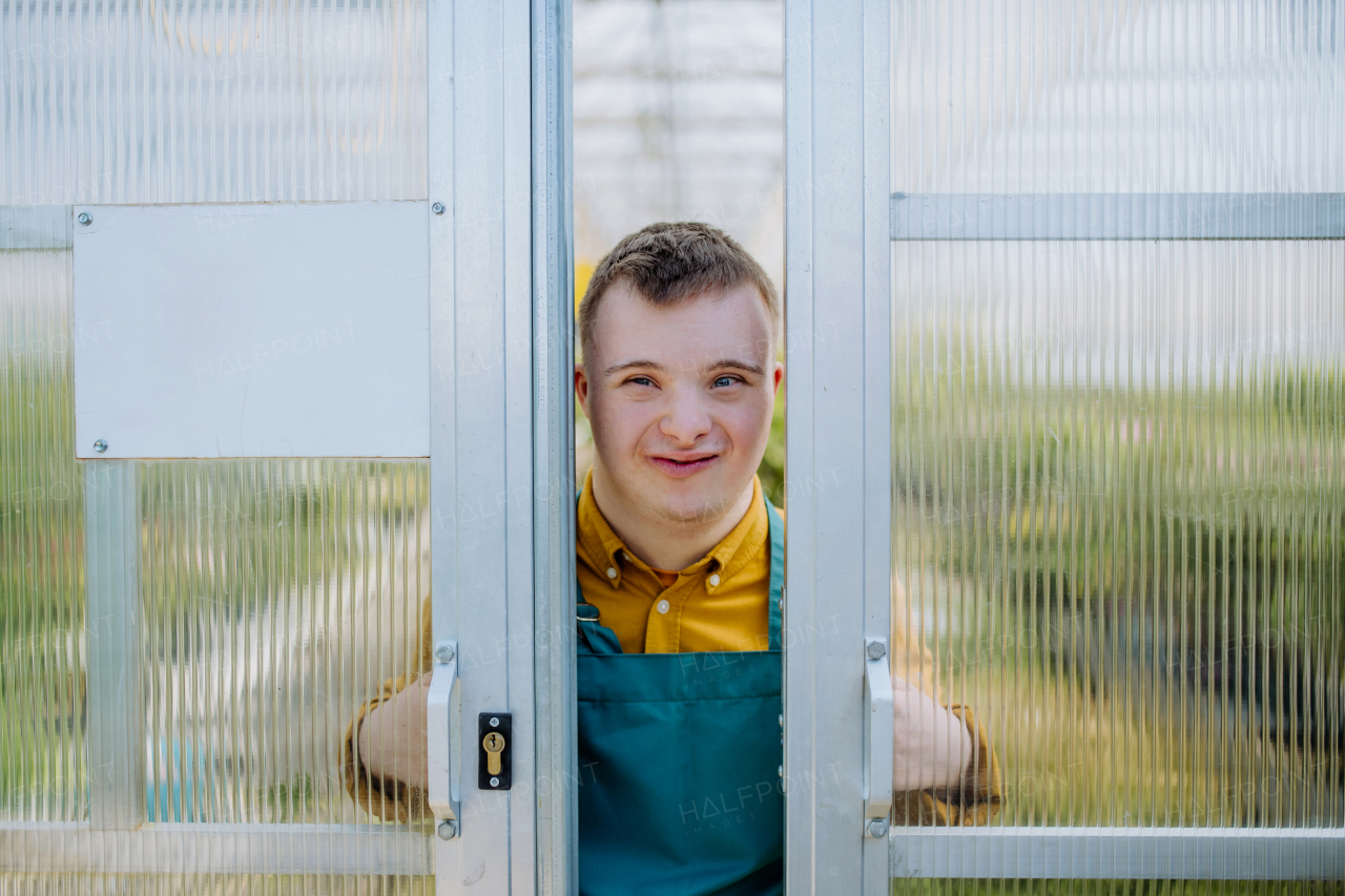 A young employee with Down syndrome working in garden centre, looking at camera.