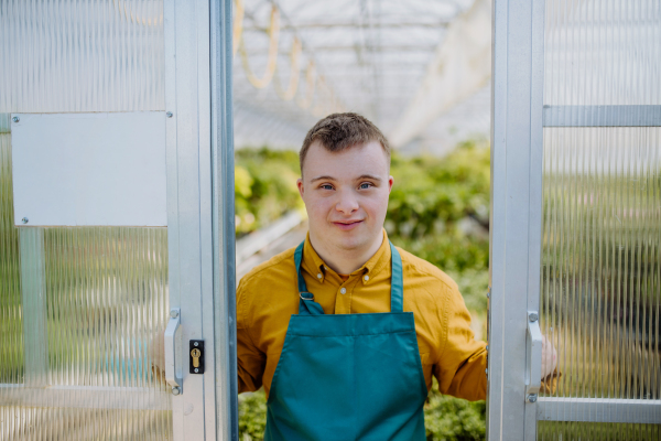 A young employee with Down syndrome working in garden centre, looking at camera.