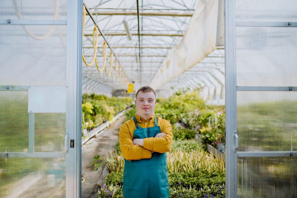 A young employee with Down syndrome working in garden centre, looking at camera.