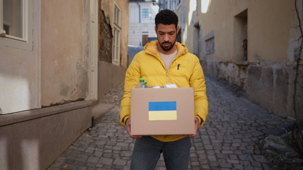 A volunteer cyrrying box with Humanitarian aid for Ukrainian refugees in street