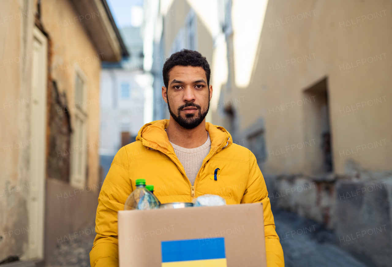 A volunteer cyrrying box with Humanitarian aid for Ukrainian refugees in street