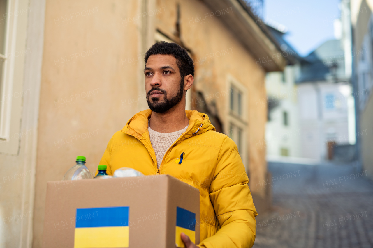 A volunteer cyrrying box with Humanitarian aid for Ukrainian refugees in street