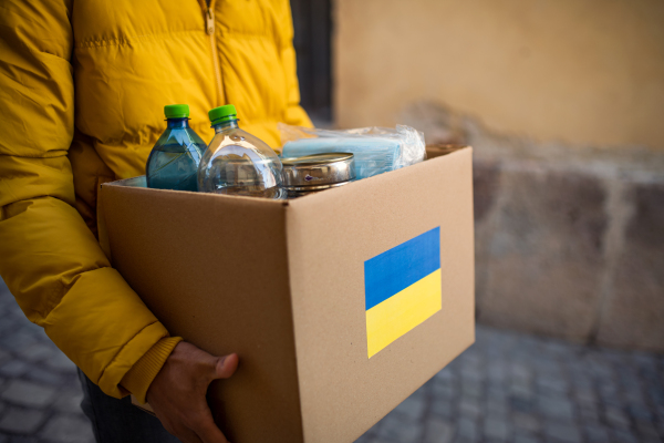 A close up of volunteer cyrrying box with Humanitarian aid for Ukrainian refugees in street