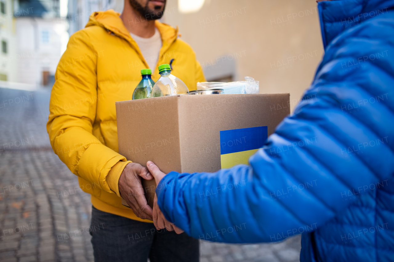 A cropped shot of volunteers collecting box with Humanitarian aid for Ukrainian refugees in street