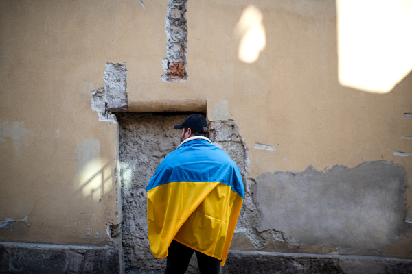 A protestor covered with blue and yellow Ukrainian flag protesting against war in Ukraine in street