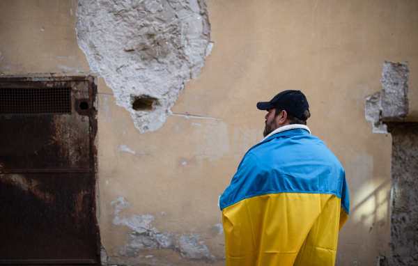 A protestor covered with blue and yellow Ukrainian flag protesting against war in Ukraine in street