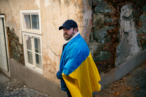 A protestor covered with blue and yellow Ukrainian flag protesting against war in Ukraine in street