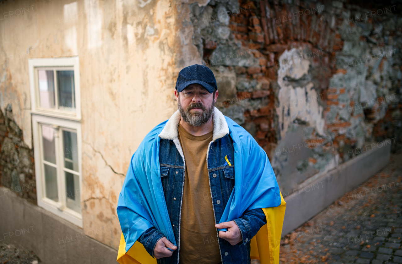 A protestor covered with blue and yellow Ukrainian flag protesting against war in Ukraine in street