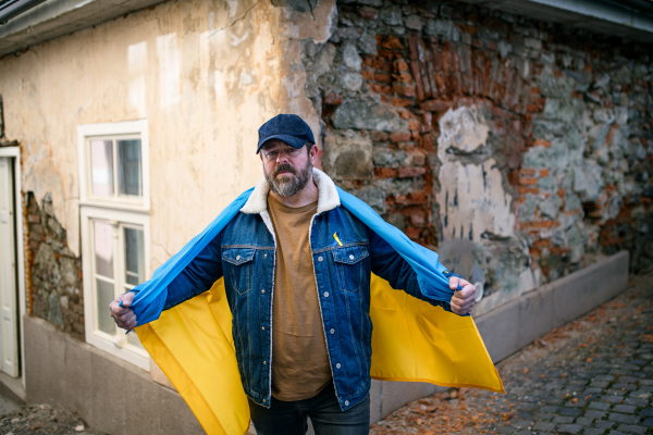 A protestor covered with blue and yellow Ukrainian flag protesting against war in Ukraine in street