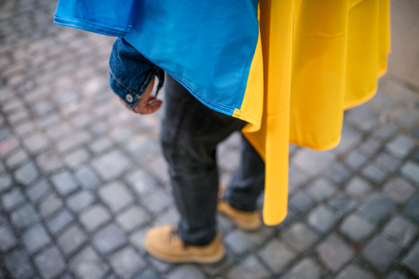 A lowsection of protestor covered with blue and yellow Ukrainian flag protesting against war in Ukraine in street