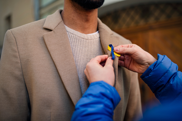 A protest organizer distributing Ukrainian blue and yellow ribbons to people protesting against war in Ukraine