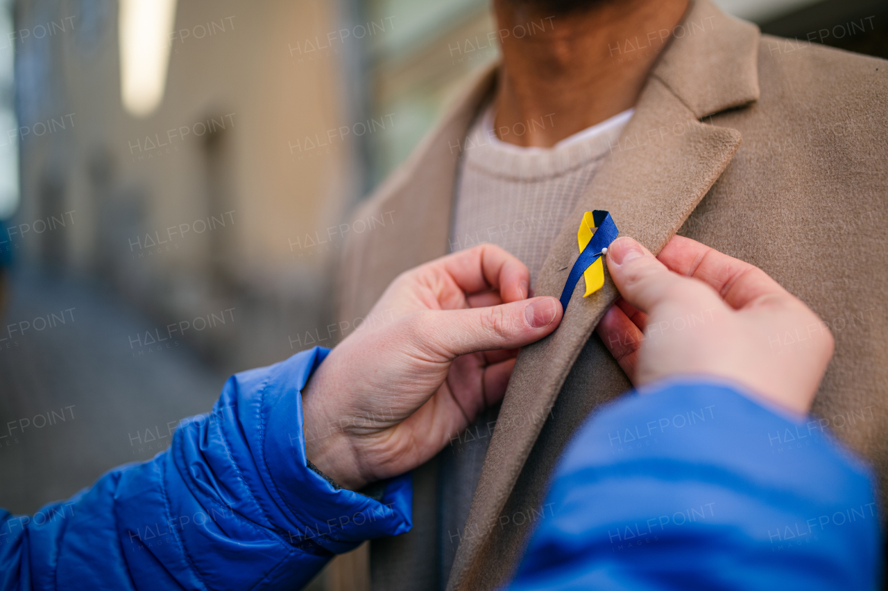 A protest organizer distributing Ukrainian blue and yellow ribbons to people protesting against war in Ukraine