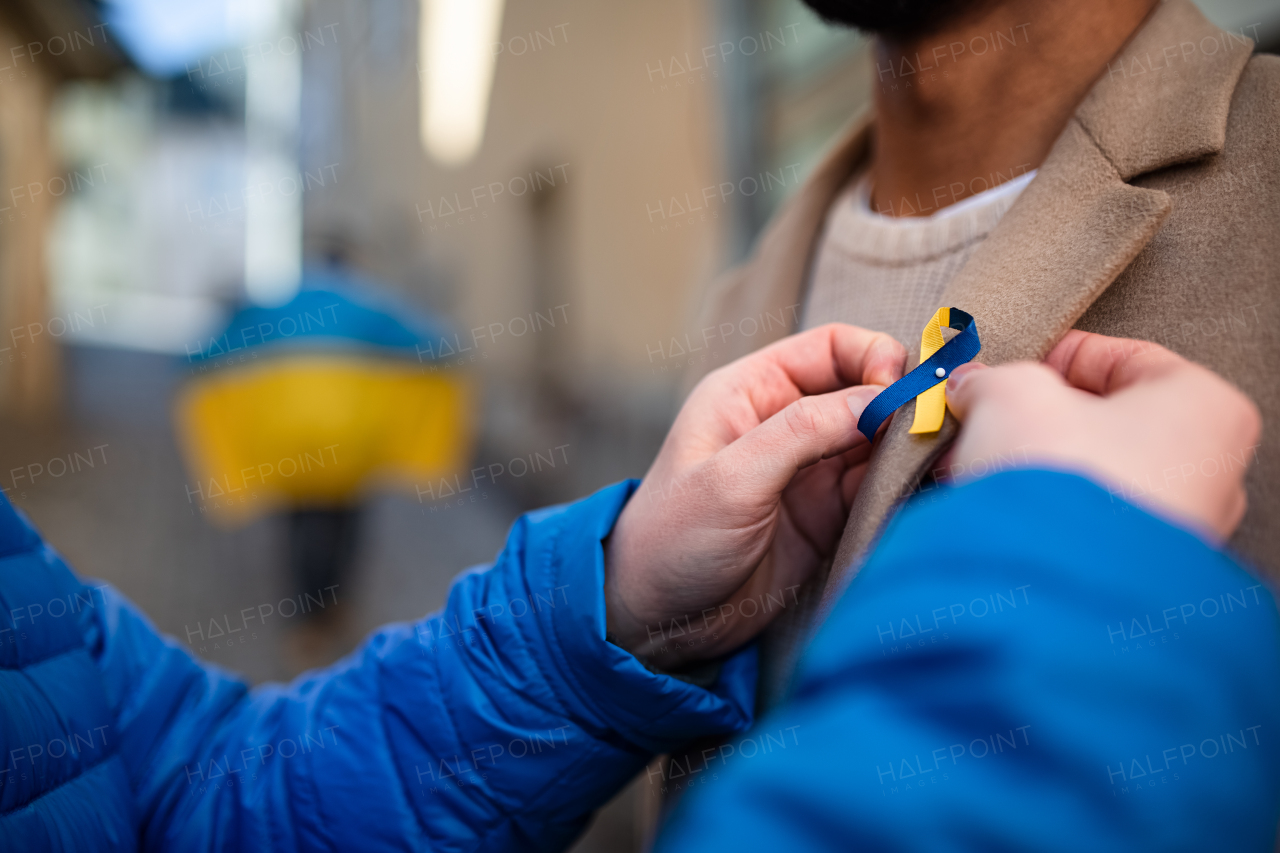 A protest organizer distributing Ukrainian blue and yellow ribbons to people protesting against war in Ukraine