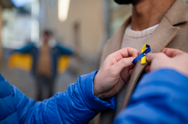 A protest organizer distributing Ukrainian blue and yellow ribbons to people protesting against war in Ukraine