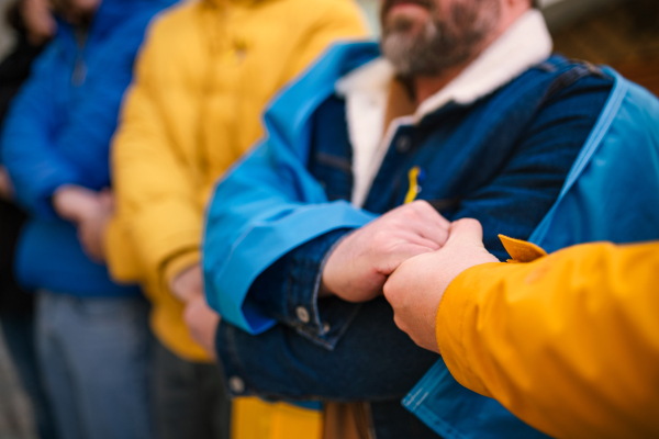 A cropped shot of protestors with Ukrainian blue and yellow ribbons and flags protesting against war in Ukraine in street