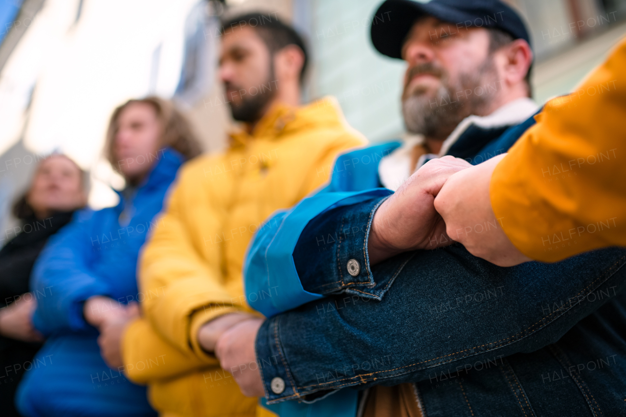 A cropped shot of protestors with in Ukrainian colors protesting against war in Ukraine in street