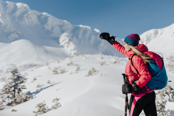 A female backcountry skier hiking to the summit of a snowy peak in the Low Tatras in Slovakia.