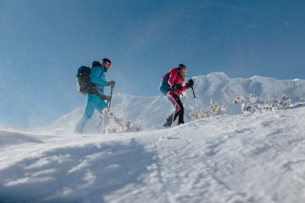 A low angle view of ski touring couple hiking up in mountains.