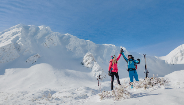 A ski touring couple high fiving on the top of mountain in the Low Tatras in Slovakia.