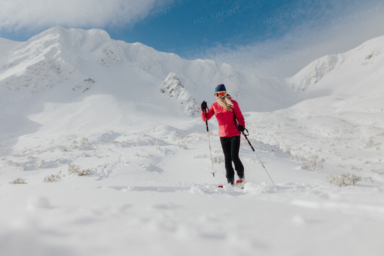 A female backcountry skier hiking to the summit of a snowy peak in the Low Tatras in Slovakia.