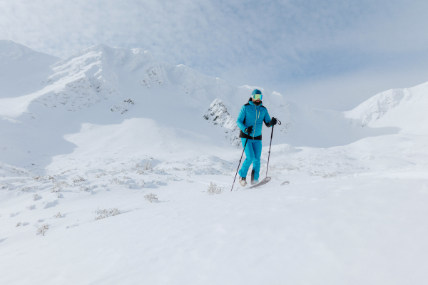 A male backcountry skier hiking to the summit of a snowy peak in the Swiss Alps