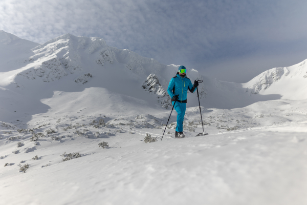 A male backcountry skier hiking to the summit of a snowy peak in the Swiss Alps