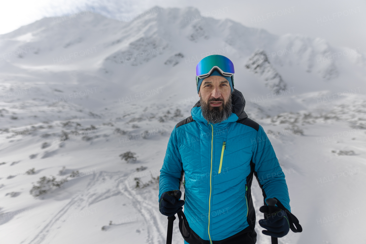 A male backcountry skier hiking to the summit of a snowy peak in the Swiss Alps