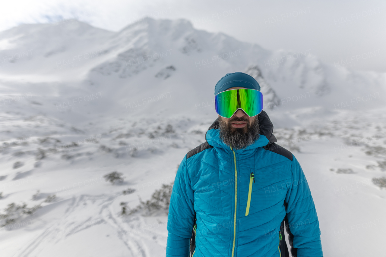 Man with ski goggles, preparing for winter skiing in snowy mountains.