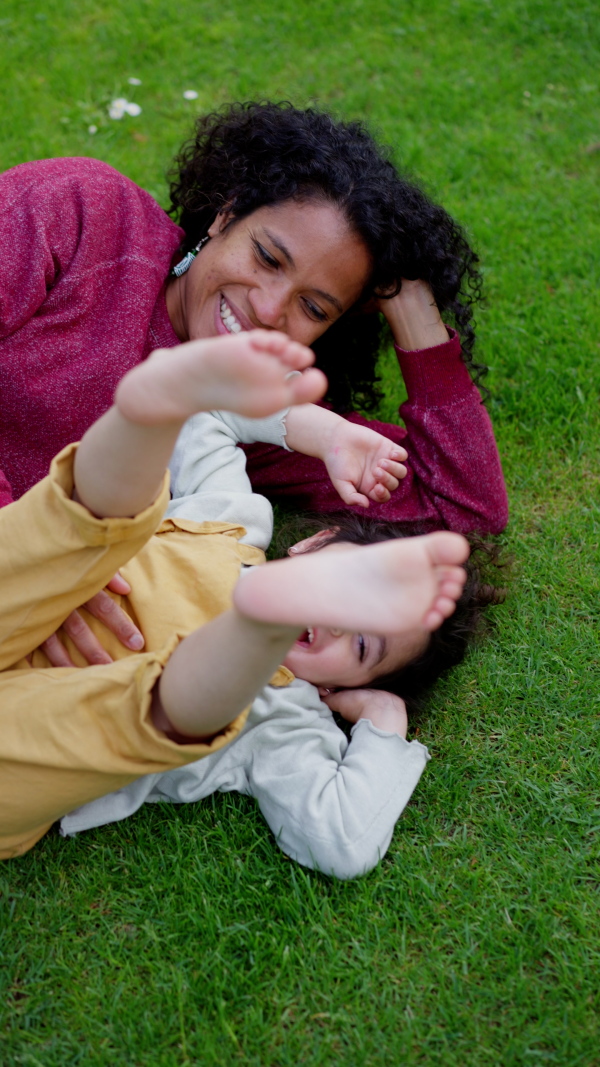 A mother and daughter lying on the grass, spending time outdoor in nature during summer