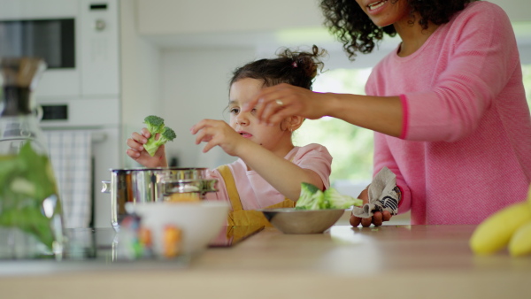 An african American mother teaching child to cook and help in the kitchen.