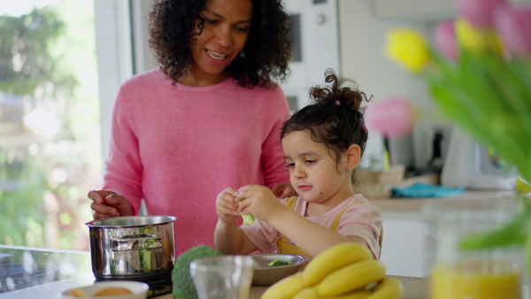 An african American mother teaching child to cook and help in the kitchen.