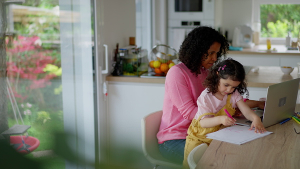 A mother working from home while child is sitting with her. Home office concept.