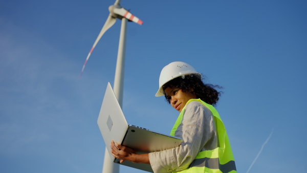 An engineer woman standing in front of wind turbines generating electricity power station. Concept of sustainability development by alternative energy