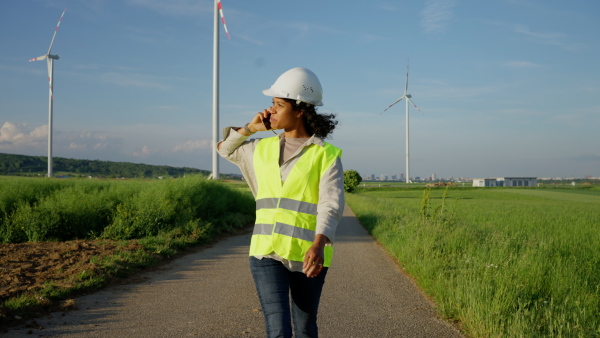 An engineer woman standing in front of wind turbines generating electricity power station. Concept of sustainability development by alternative energy