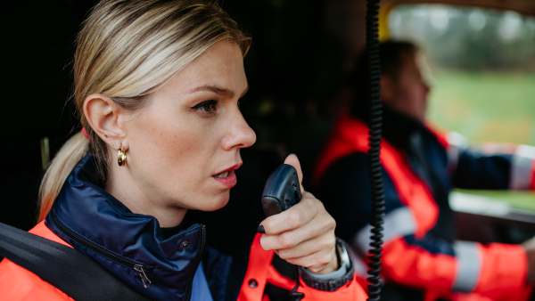 Portrait of a young woman doctor sitting and talking in to walkie-talkie in ambulance car.