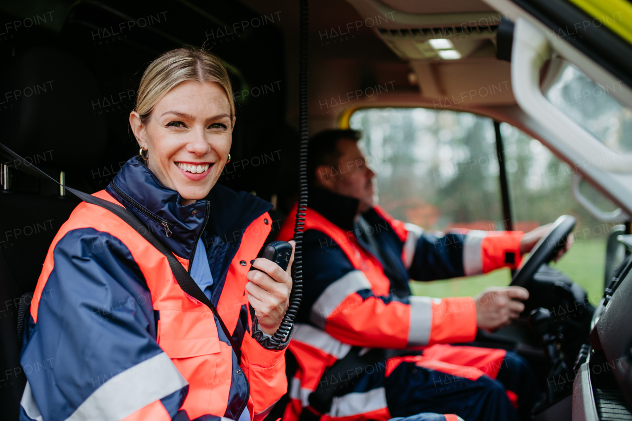 Portrait of a young woman doctor sitting and talking in to walkie-talkie in ambulance car.