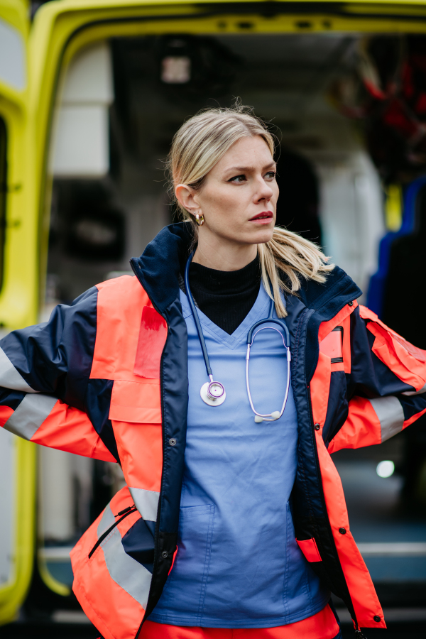 Portrait of a young woman doctor standing in front of ambulance car.