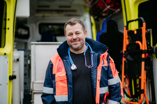 Portrait of rescuer standing in front of ambulance car.