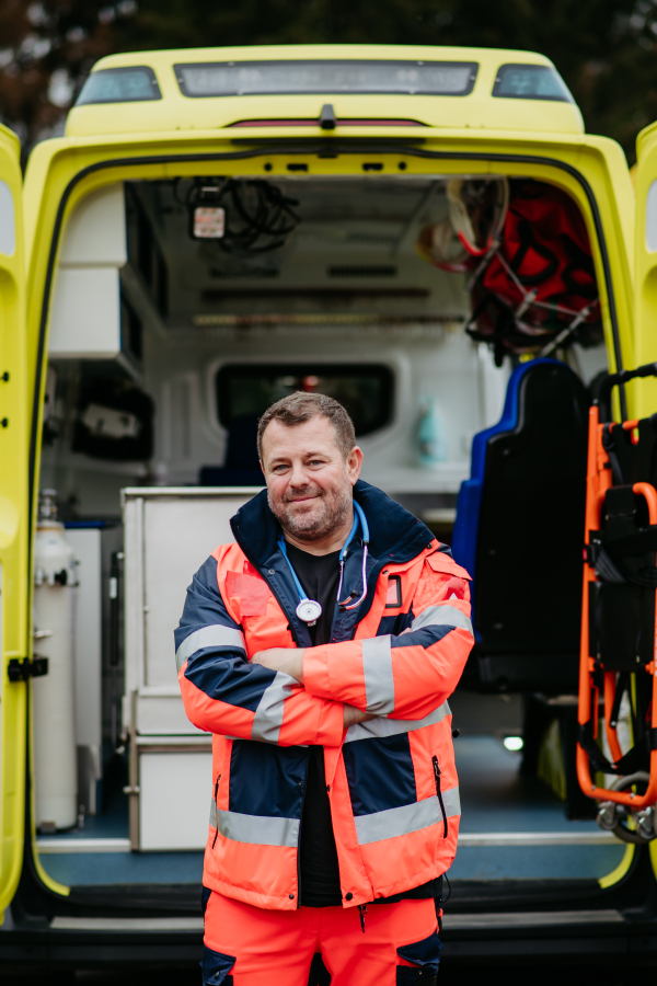 Portrait of rescuer standing in front of ambulance car.