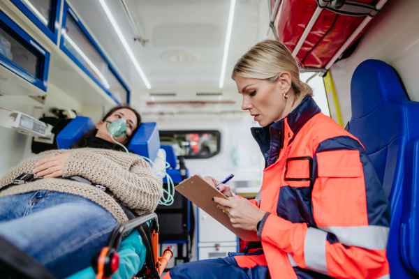 Rescuer taking care of patient, writing the medical record.